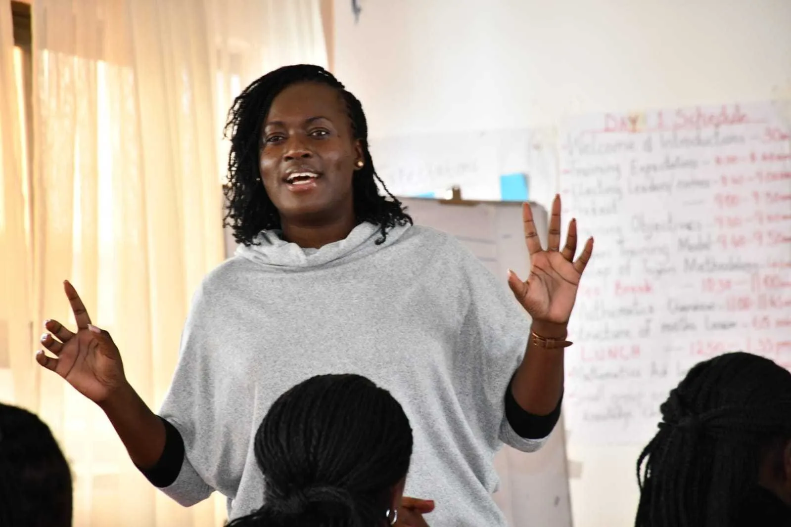 Trainer speaking with raised hands to teachers, in front of a training schedule