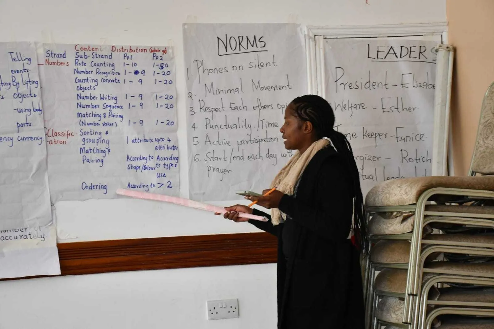 Trainer pointing to a chart of numeracy content during a teacher training session