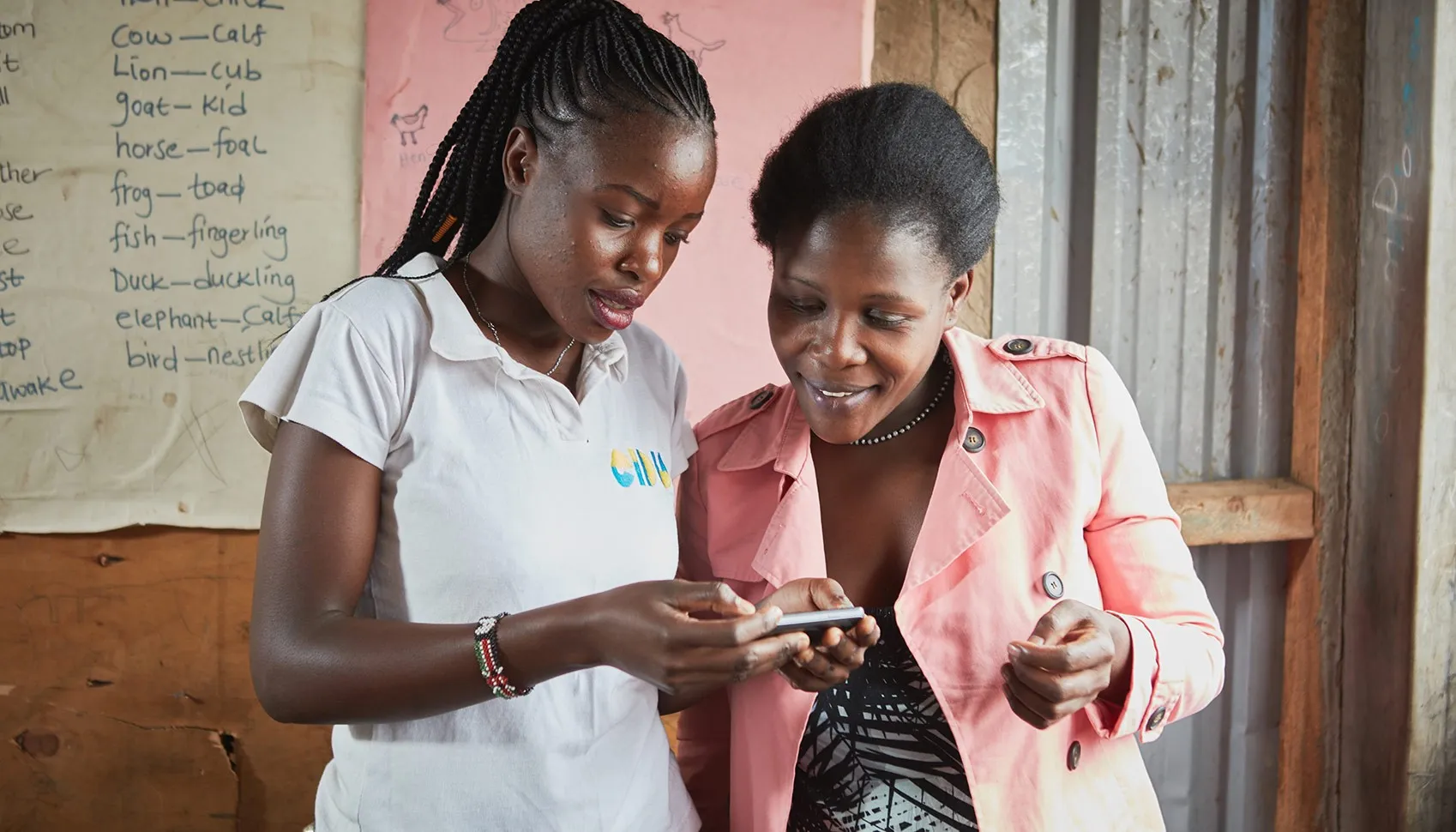 EIDU officer and a teacher looking at a phone together and talking in a classroom