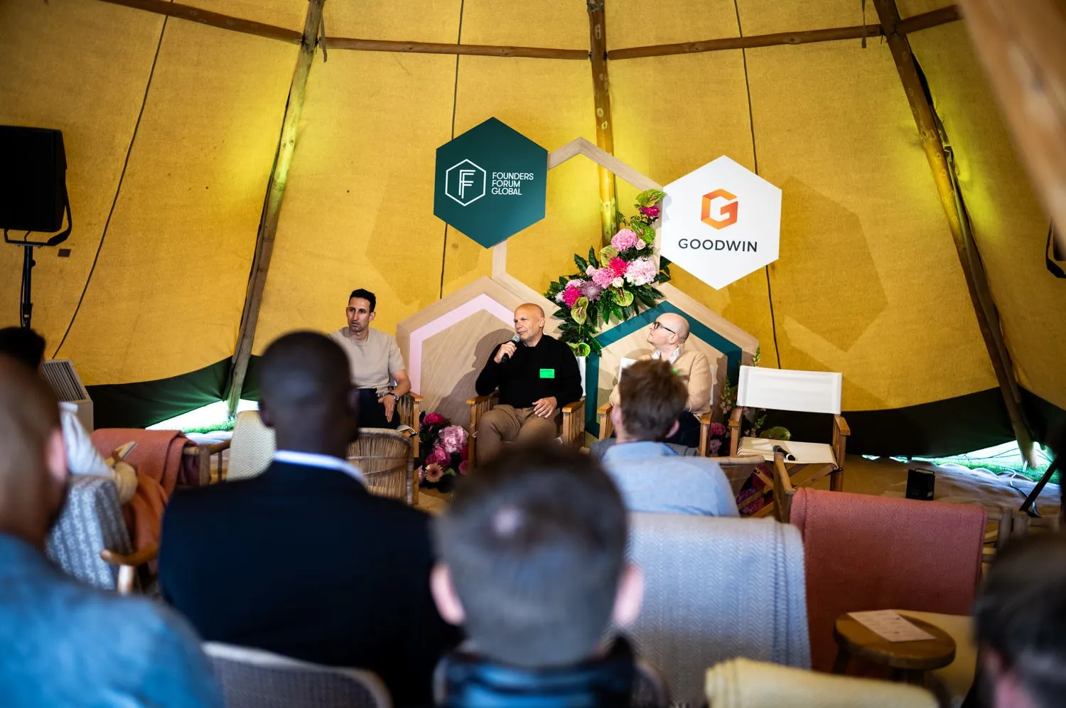 Panel discussion on stage in a tent at Founders Forum Global, seen from the audience