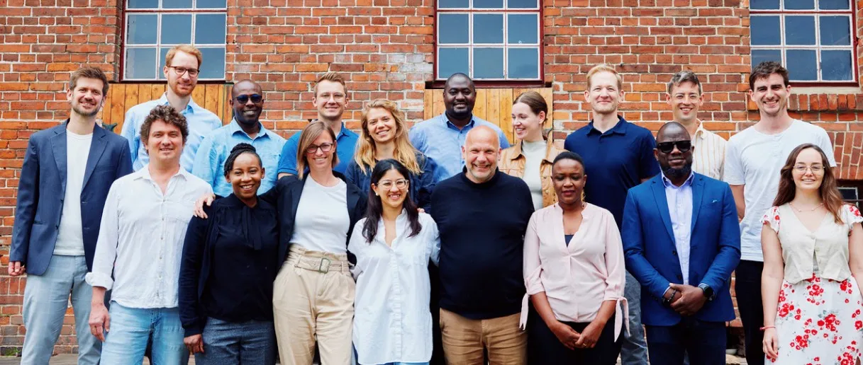 EIDU team members smiling together in front of a red-brick building