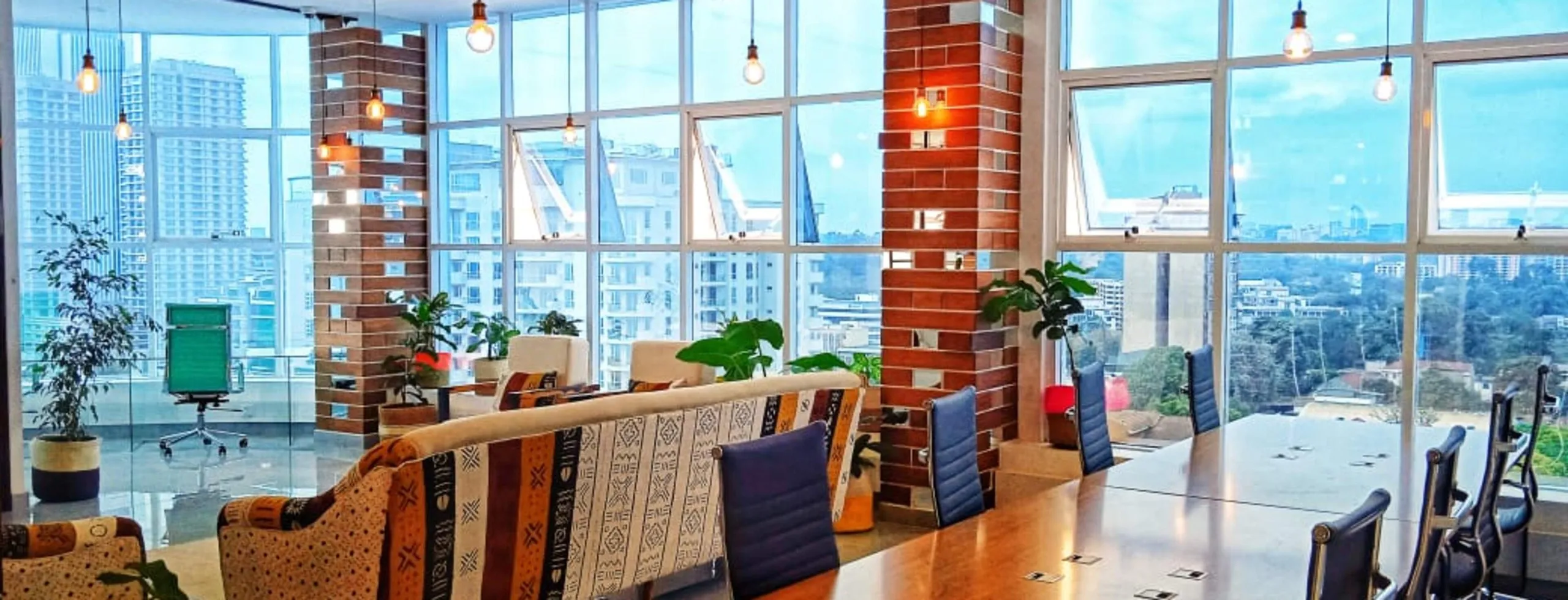 Open-plan Nairobi office with brick pillars, a long meeting table and floor-to-ceiling windows over the city