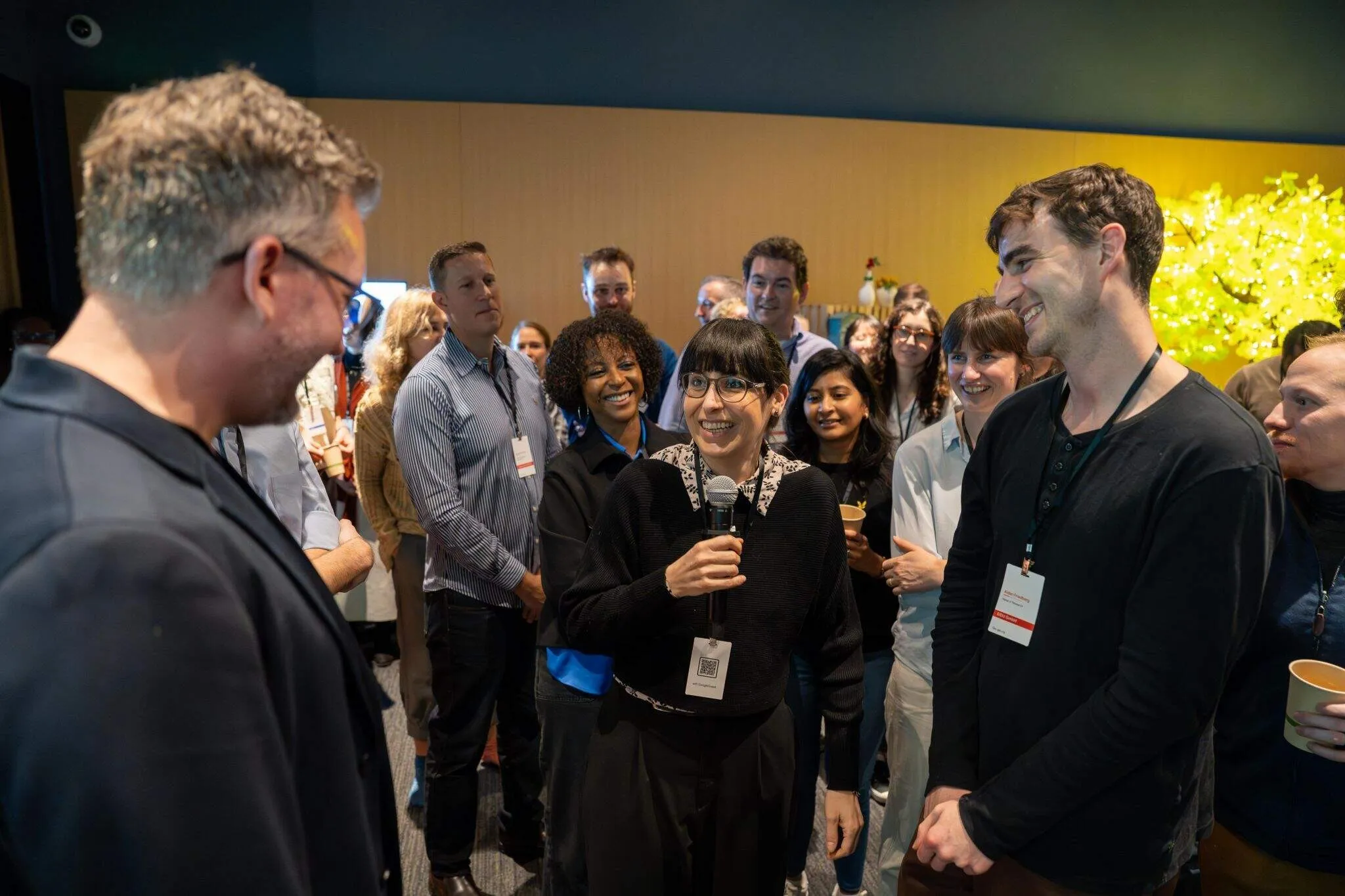 Woman with a microphone talking to a man as a smiling crowd looks on at an event