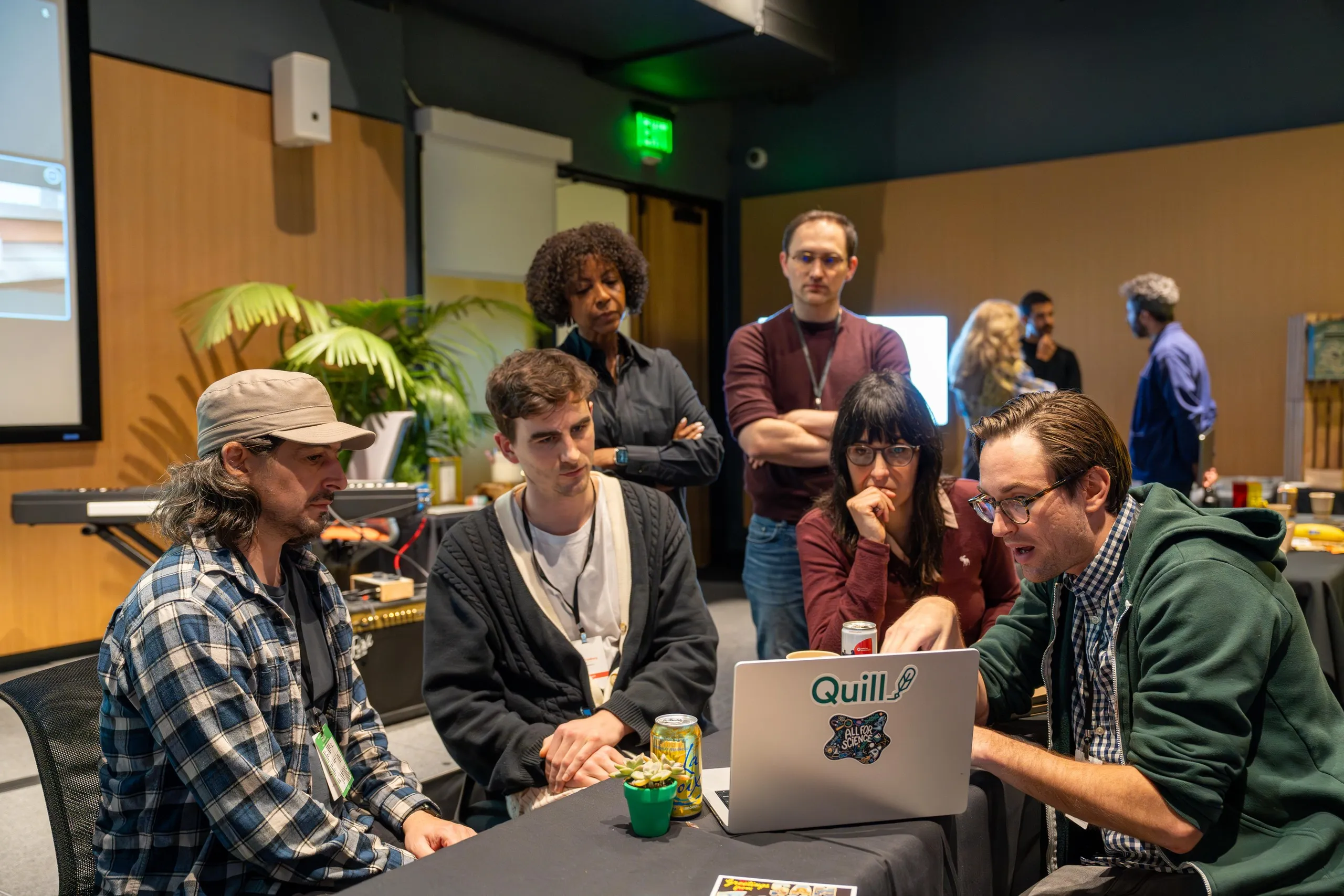 Group gathered around a laptop at a workshop as one person explains something on screen