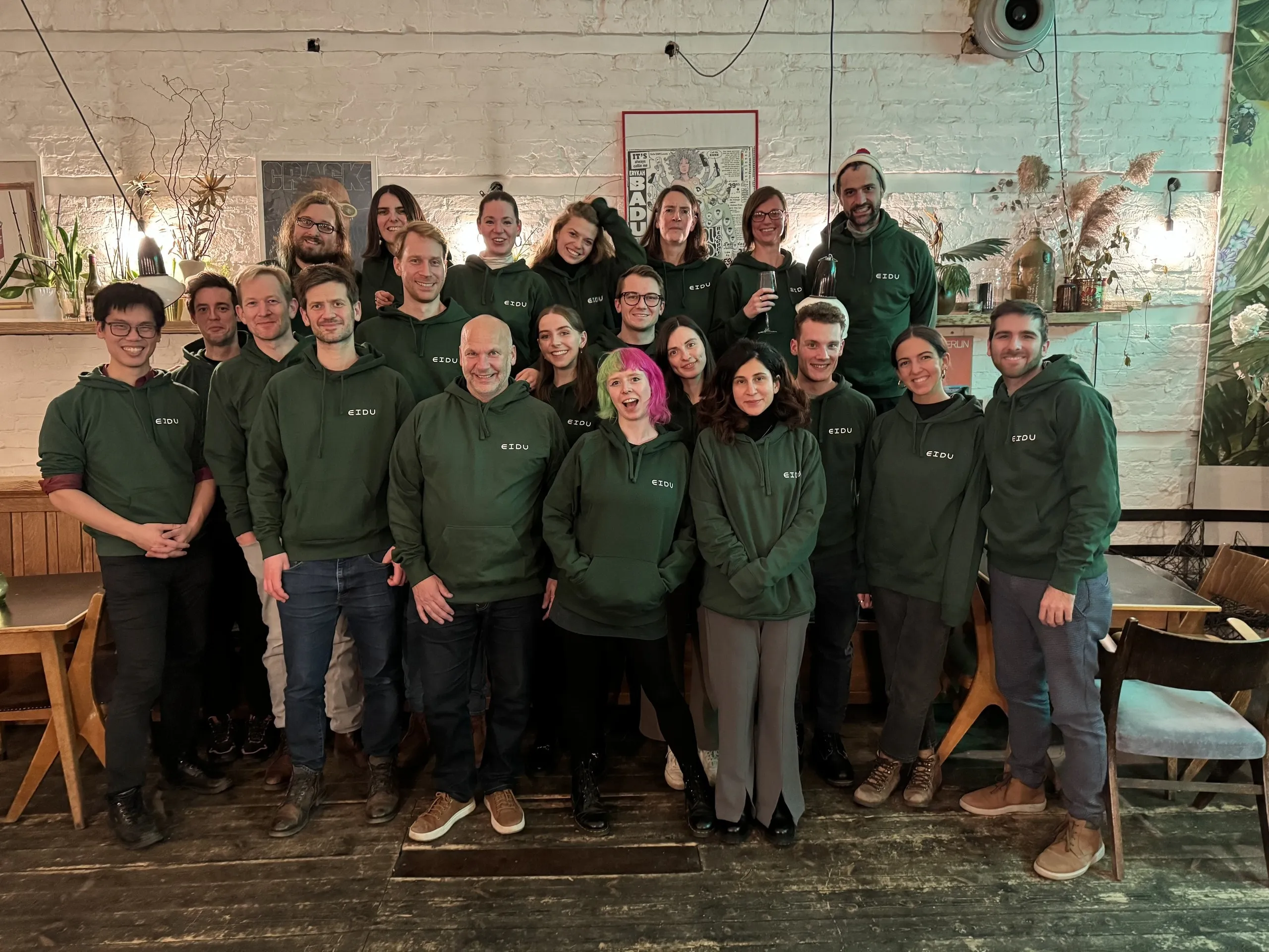 EIDU team members posing together in matching green EIDU hoodies
