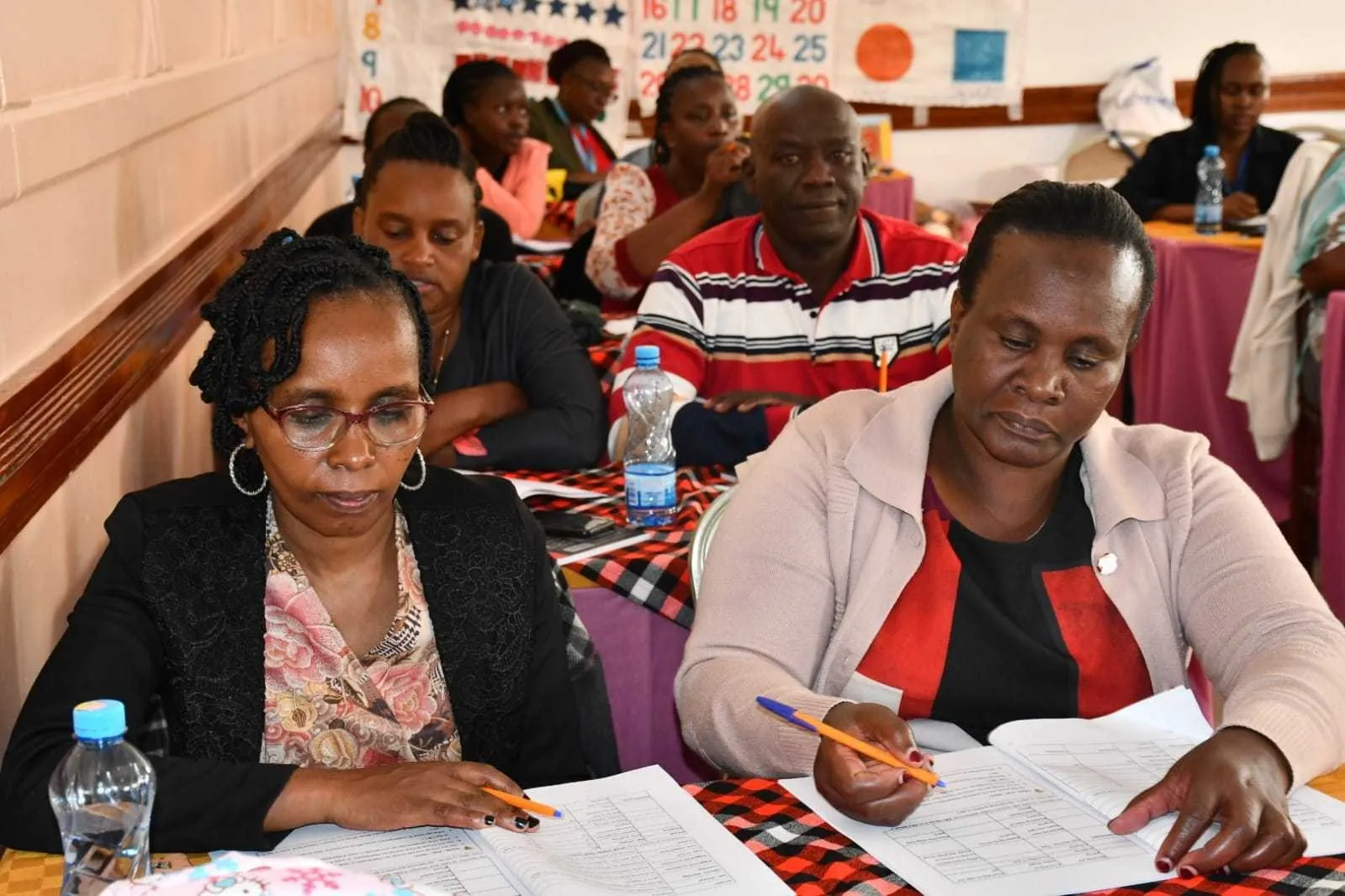 Teachers at tables working through printed training materials